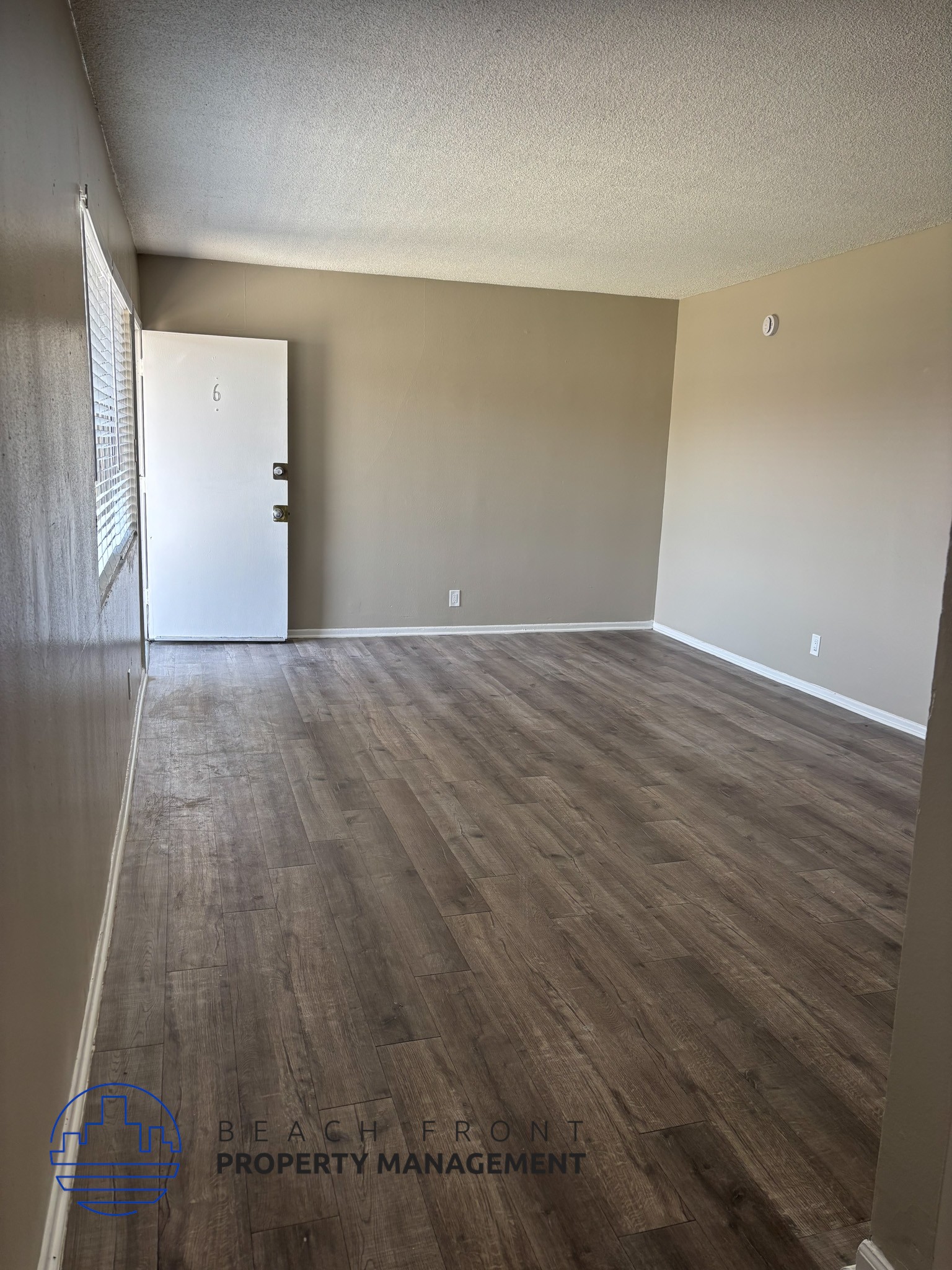 , A room with wooden flooring and a white door.,A room with wooden flooring and a white door.